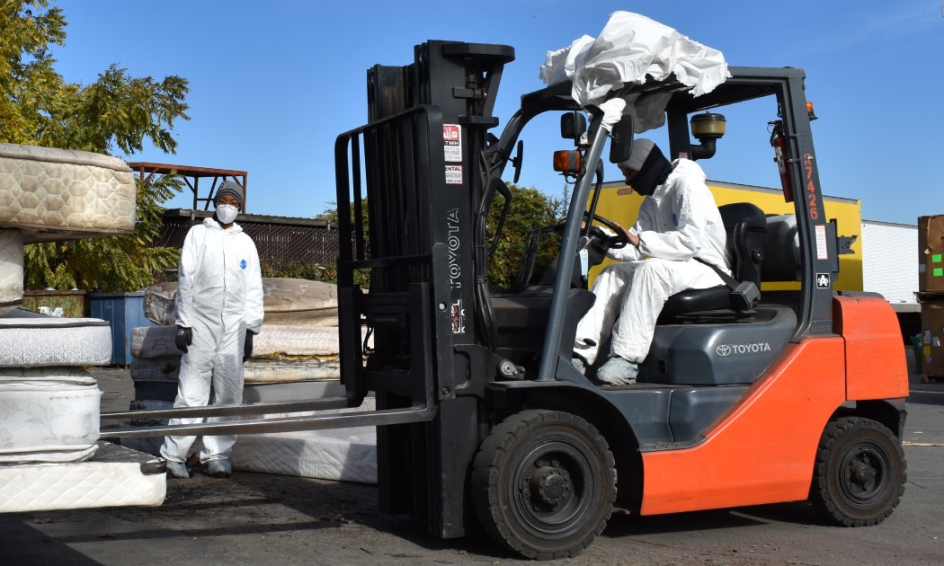 Staff using a forklift to move mattress.
