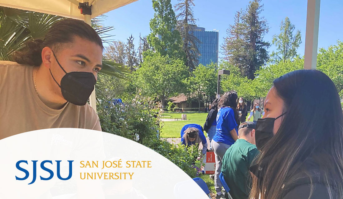 Corpsmember talks to student at campus event with SJSU logo